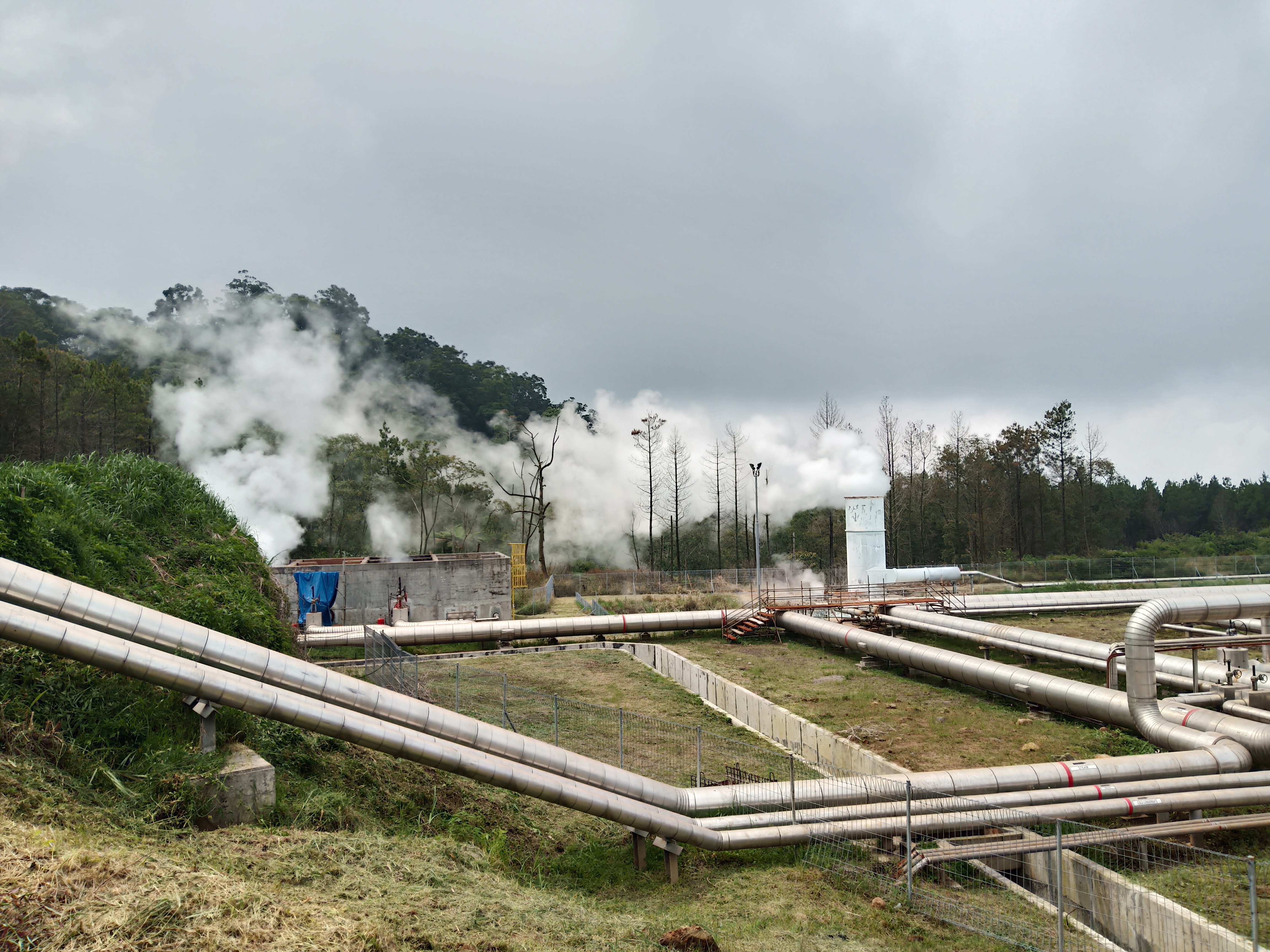 Piping and equipment at a geothermal power plant in a forested area of Indonesia.