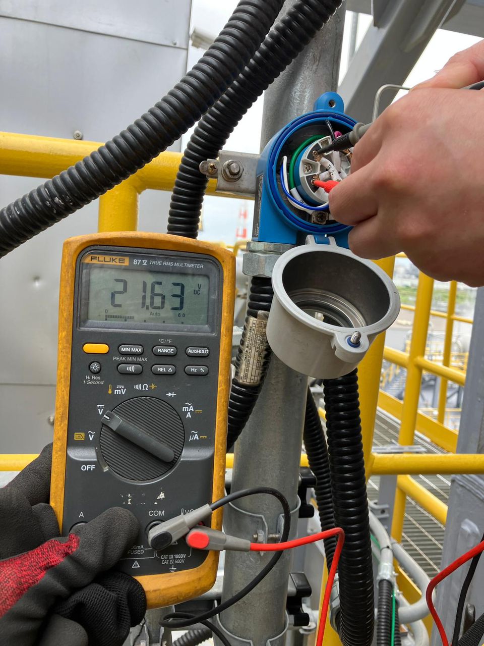 Multimeter measurement on instrumentation equipment, showing the technician's hands.